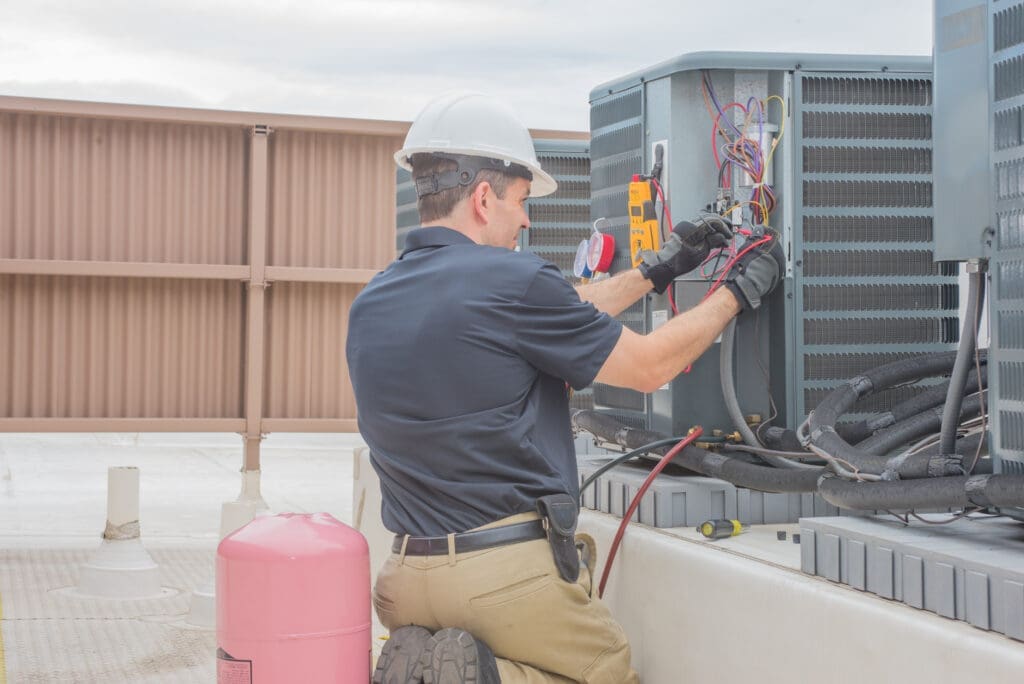 A commercial HVAC company tech checking a condenser.