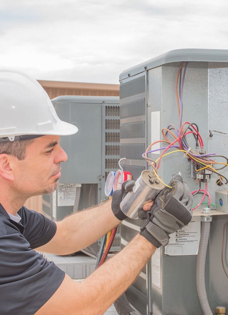 An HVAC technician working on a capacitor.