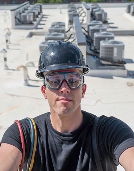 HVAC Tech taking selfie with new HVAC work in the background